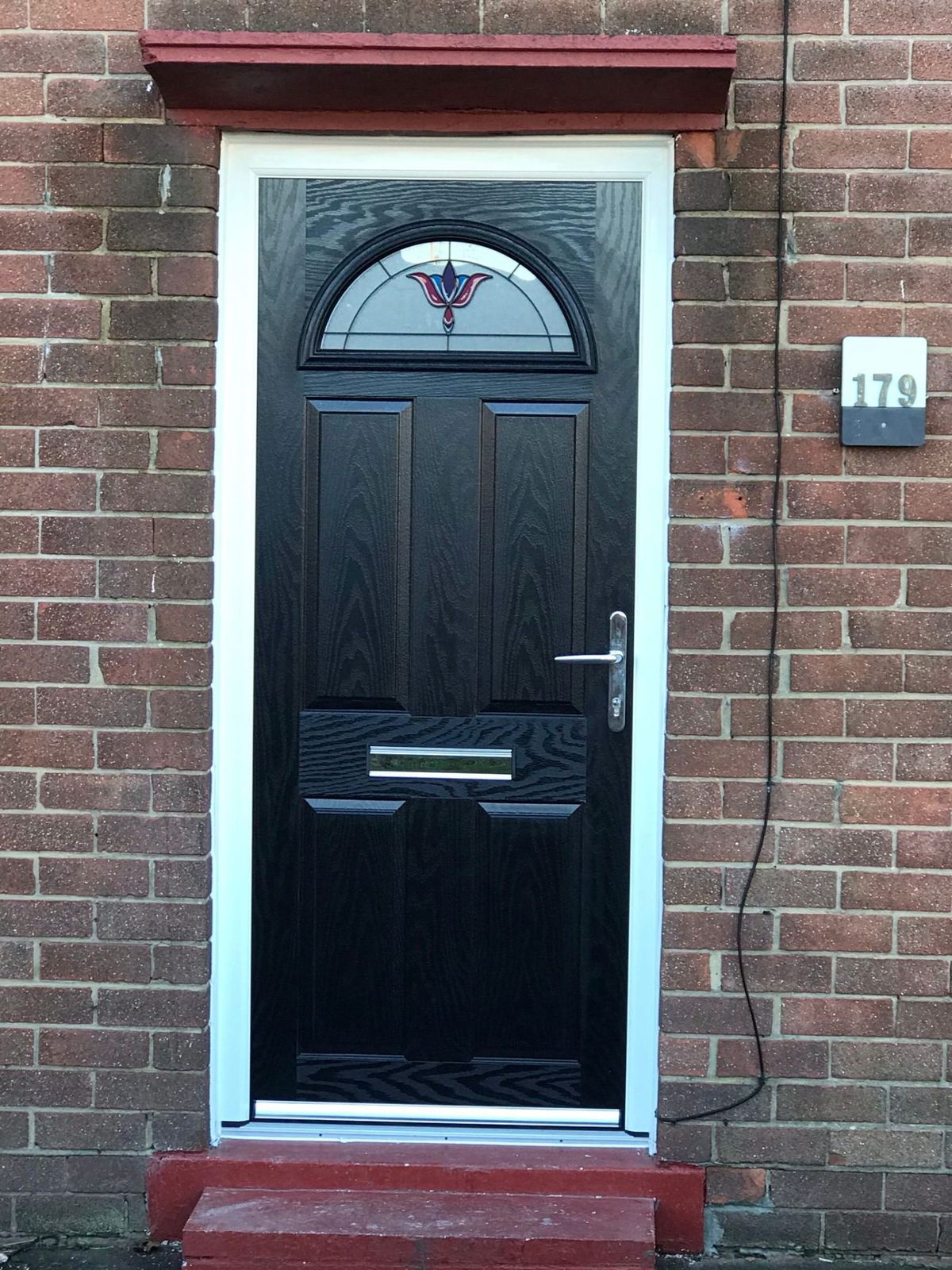 Black composite door with sunburst decorative glass