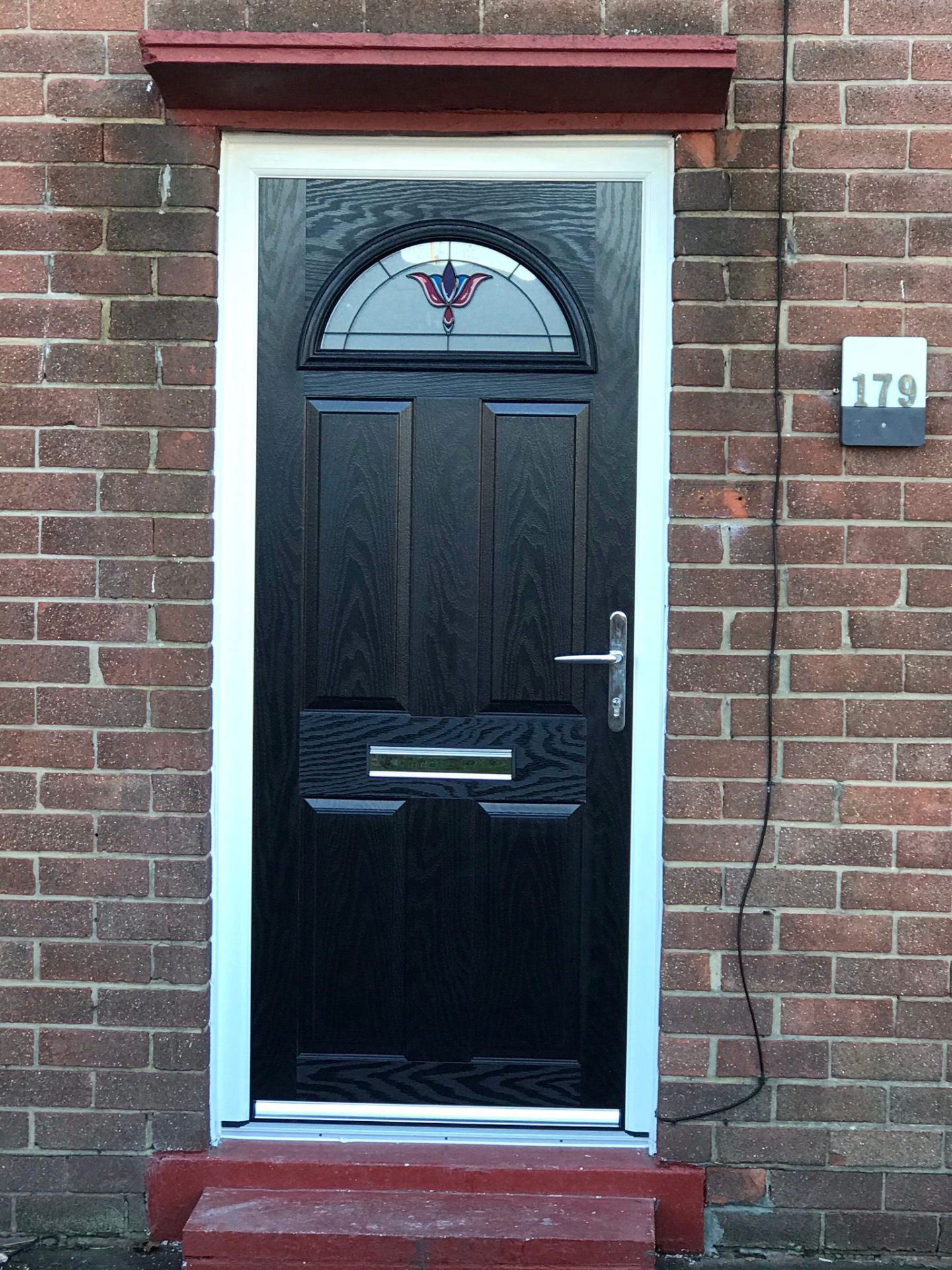 Black composite door with sunburst decorative glass