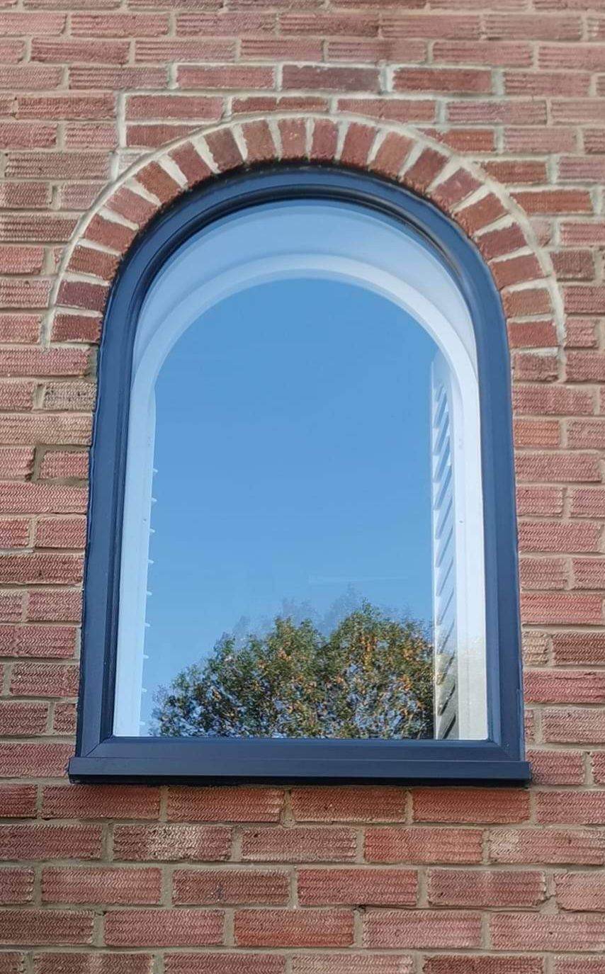 Anthracite grey arched window installed in red brick wall
