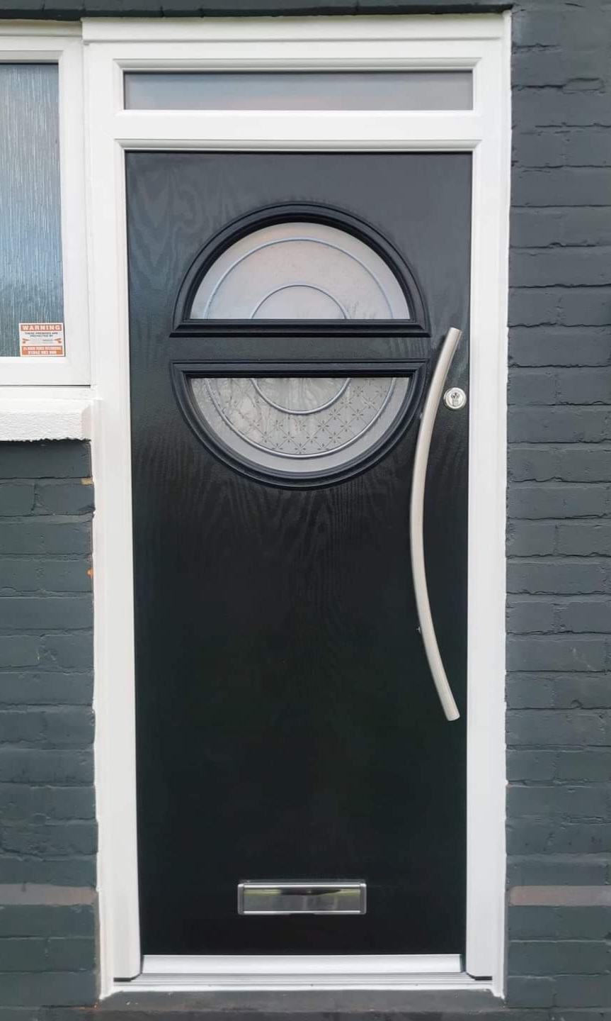 Black composite door with circular decorative glass and curved chrome handle